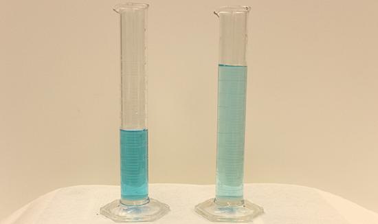 This figure shows two graduated cylinders side-by-side. The first has about half as much blue liquid as the second. The blue liquid is darker in the first cylinder than in the second.