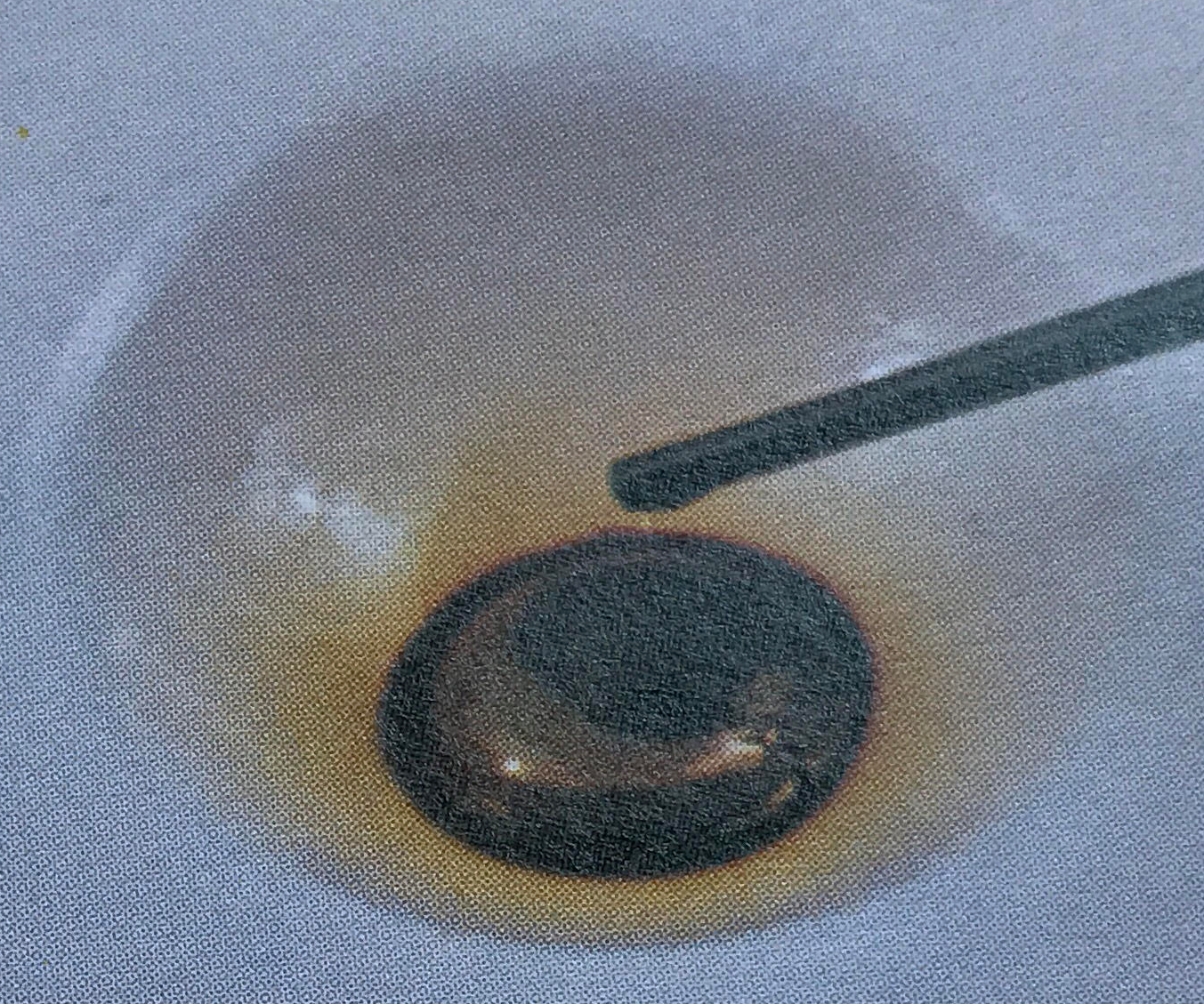 Metallic liquid rests on a pool of a deep brown liquid.