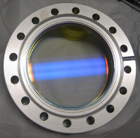 A reflective piece of circular glass is shown within a circular sheet of metal.