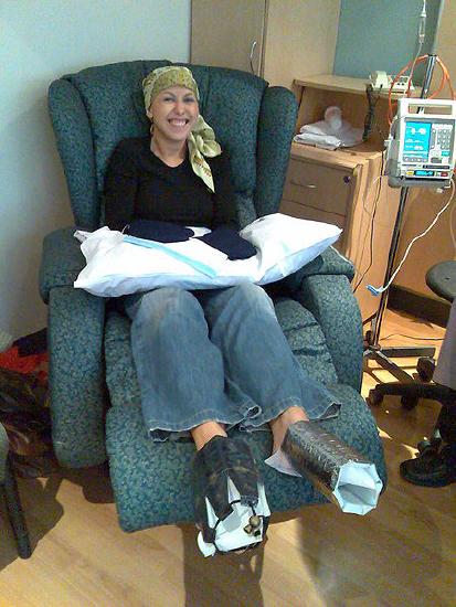Photo of a patient sitting in a chair with her hands and feet wrapped in cooling pads and thermal insulators.