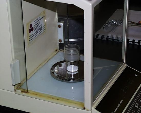 A sample sits in a glass container on a balance.