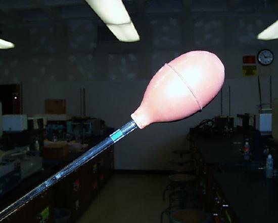 Volumetric pipet shown with a rubber bulb attached to the upper end.