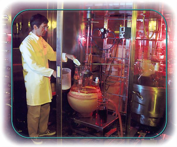 Químico en ambiente industrial añadiendo reactivo a equipos de síntesis