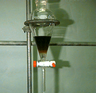 Embudo separador con líquido marrón por encima del líquido transparente
