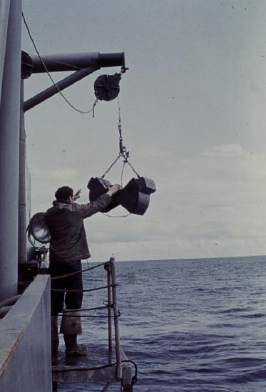 A man reaches up to a bag suspended about the water source.