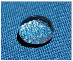 A water droplet sits atop the fluorosurfactant treated fabric rather than sinking in.