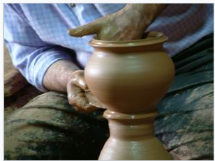 Man sculpts a clay pot that is symmetrical when split vertically in the middle.