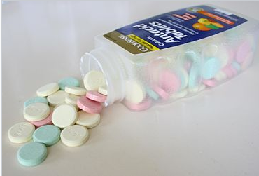 Las tabletas antiácidas se derraman de su botella sobre una superficie.