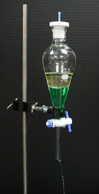 En el embudo de separación, el aceite se encuentra sobre el agua coloreada.