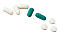 White and green pills scattered on a white backdrop.