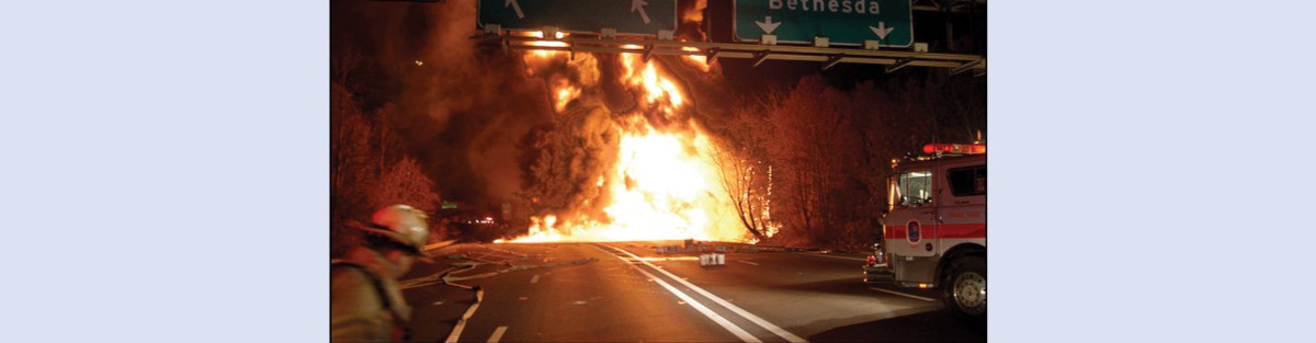 A picture shows a large ball of fire burning on a road. A fire truck and fireman are shown in the foreground.