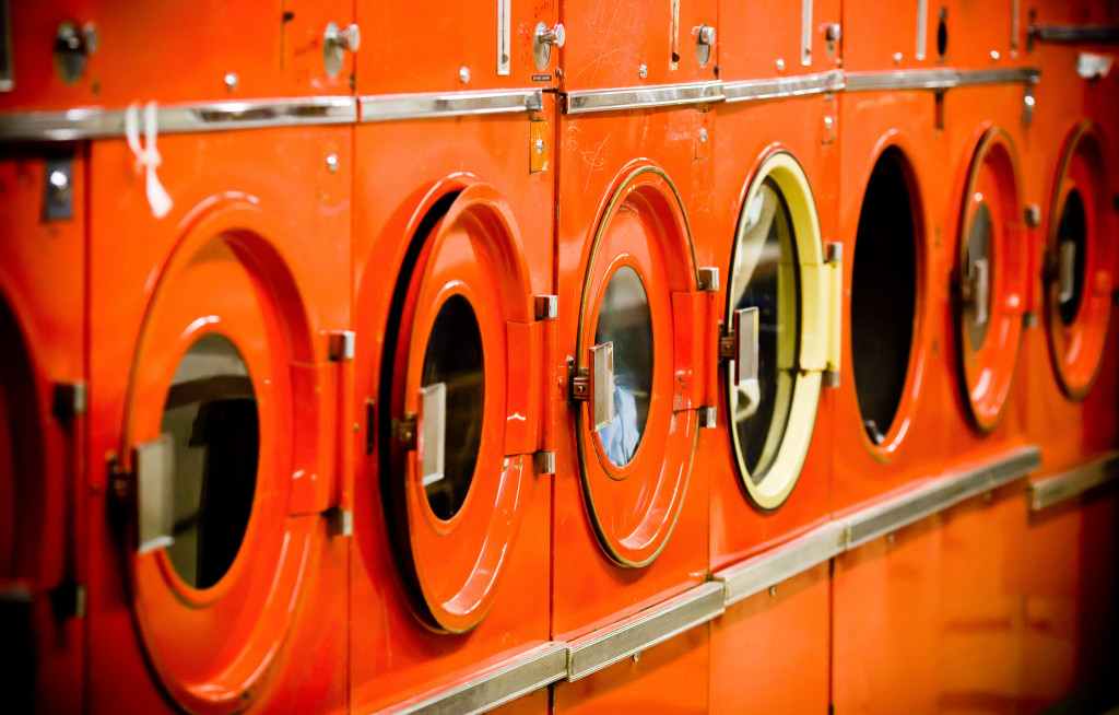 Photo of a row of orange coin-operated washing machines.
