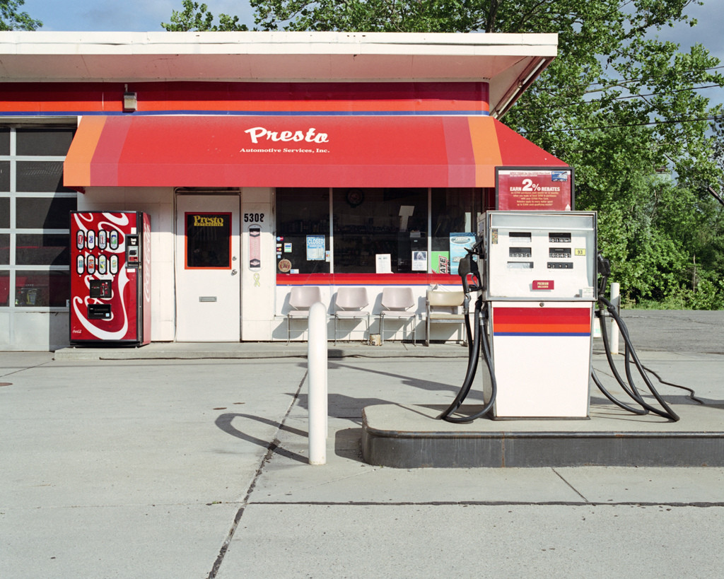 Photo of a small red and white gas station and gas pump.