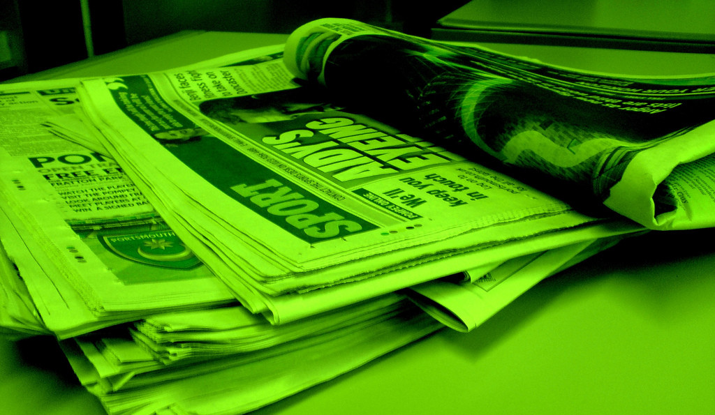 Photo of four folded newspapers; photo is very green