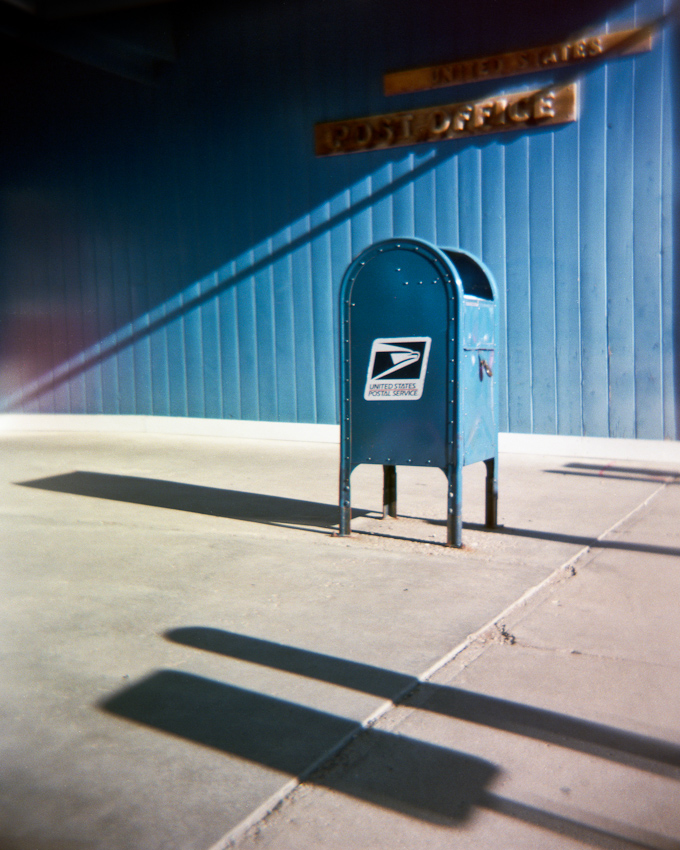 Photo of a mailbox in front of a U.S. Post Office building.