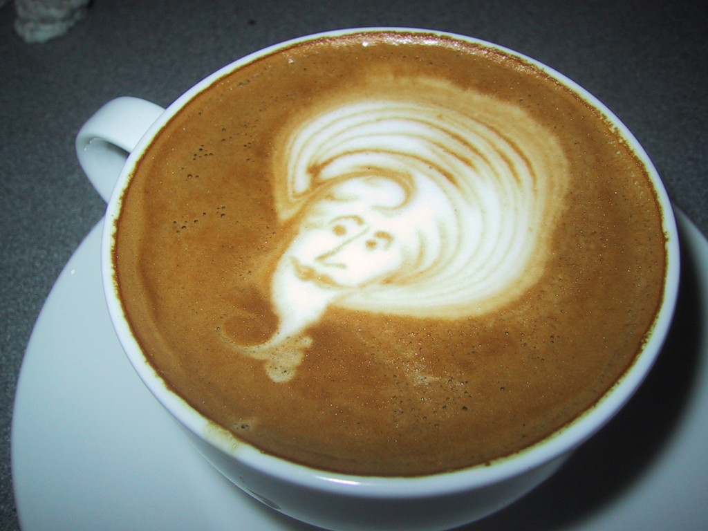 Photo of a cappuccino with a genie picture artfully drawn in the foam. An example of coffee "art."