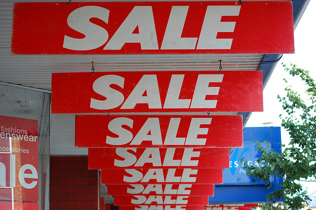 Image of repeated, excessive "Sale" signs hanging outside the front of of a store.
