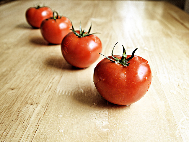 Image of four juicy, red tomatoes on a countertop.