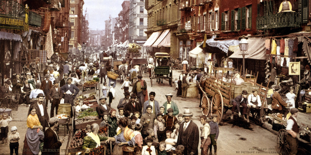 Bustling street in New York City in 1900, showing covered wagons, street vendors, and people of all ages.