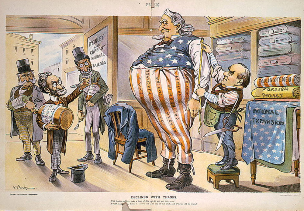 A very large and fat Uncle Sam gets measured by a tailor. The names of territories are written on his trousers.