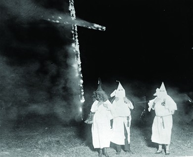 A photograph shows several hooded Klan members standing in front of a burning cross.