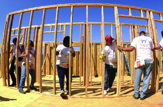 An image of several people working together to build the wooden framework of a building.