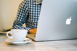 man sitting at a computer with a teacup