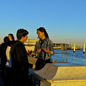 Young man and woman talking on a crowded sea wall