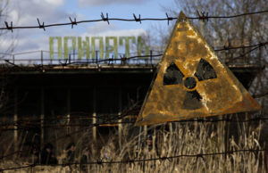 Dirty radioactive sign handing from fence.