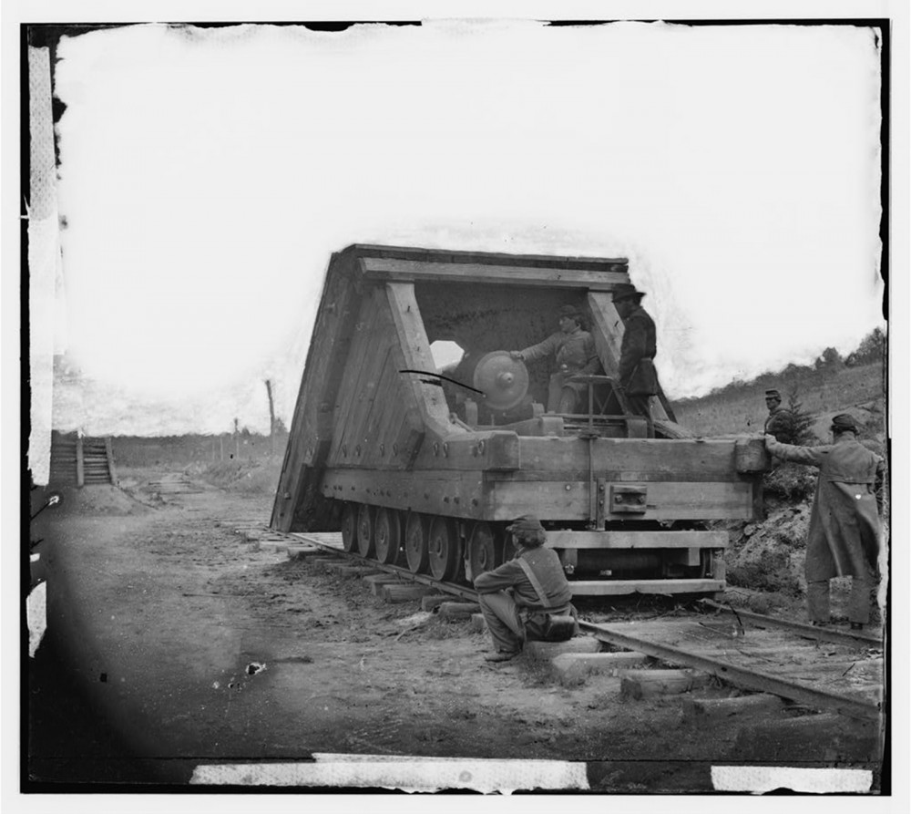 Men by a large cart on a train track.