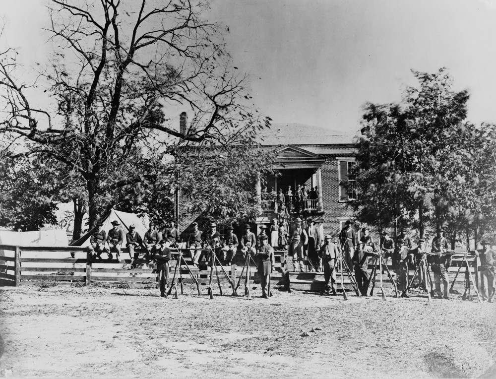 Photograph soldiers in front of a large house.