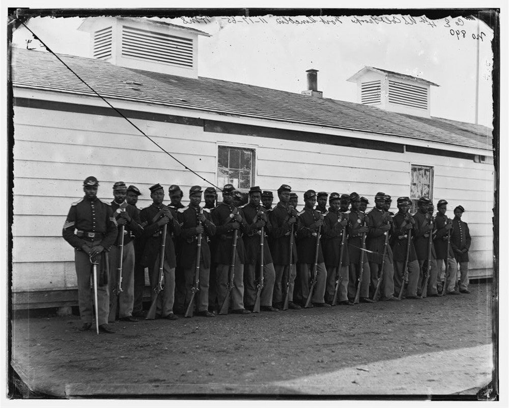 A line of black men in uniform holding rifles.