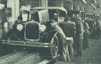 A photograph shows assembly line workers producing Ford automobiles.