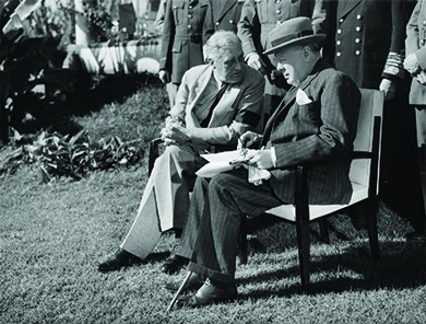 A photograph shows Winston Churchill and President Roosevelt seated outdoors in chairs, convening over papers, with a row of officials standing behind them.