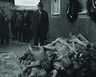 A U.S. senator, congressional committee member, and several other officials examine a massive heap of emaciated corpses at the Buchenwald concentration camp.