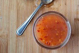 Bowl of sweet chili sauce with a spoon next to it.