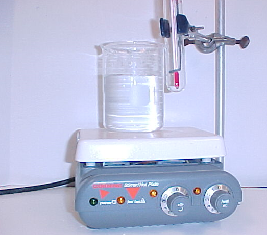 experimental setup showing water bath with test tube containing thermometer and stirring rod attached to a stand on hot plate