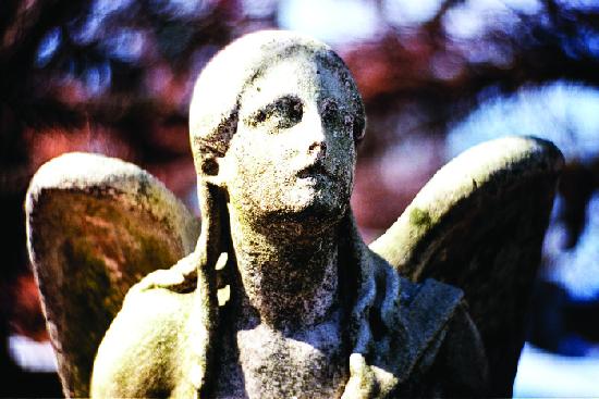 A photograph is shown of an angel statue with effects of weathering diminishing facial features.