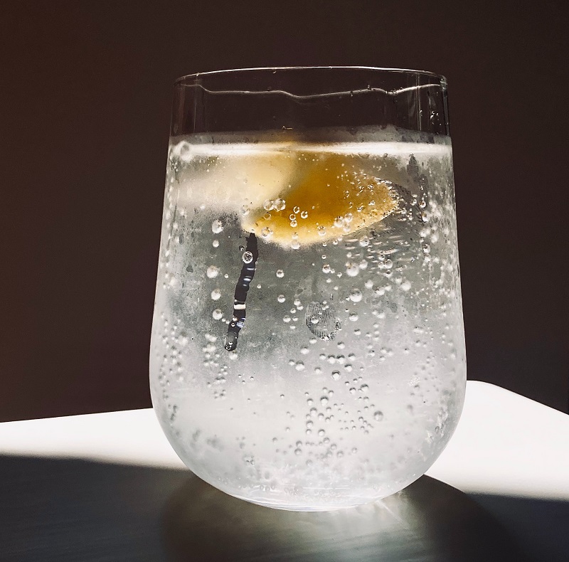 Taza con una bebida carbonatada transparente y una rodaja de limón.