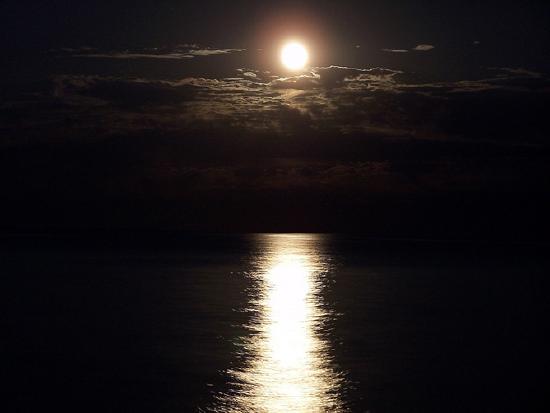 photograph of the moon reflecting off the water at night.