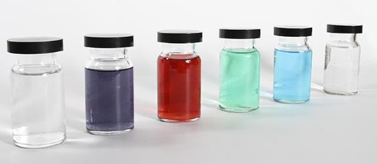 There are six containers that are each filled with a different color liquid. The first is clear, followed by purple, red, teal, blue, and the last one is also clear.