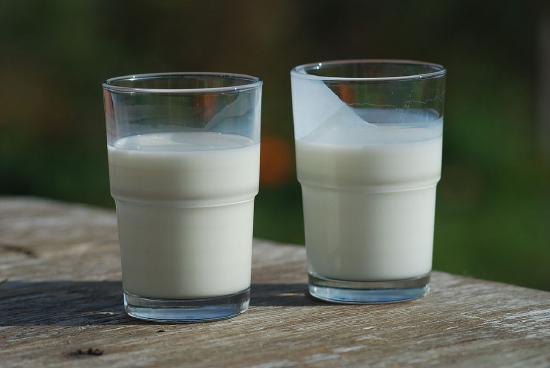 Two glasses of milk placed on a wooden table. 