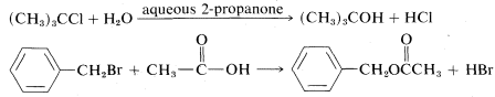 Reacción superior: (C H 3) 3 C C L más H 2 O se hace reaccionar con 2-propanona acuosa para obtener (C H 3) 3 C O H más H C L. Reacción inferior: Anillo de benceno con un sustituyente C H 2 B R más C enlace sencillo C doble enlace O y enlace sencillo O H va a benceno con un sustituyente C H 2 O C doble enlace O C H 3 más H B R.
