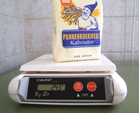 Bag of flour sitting on a scale that reads 243 grams.