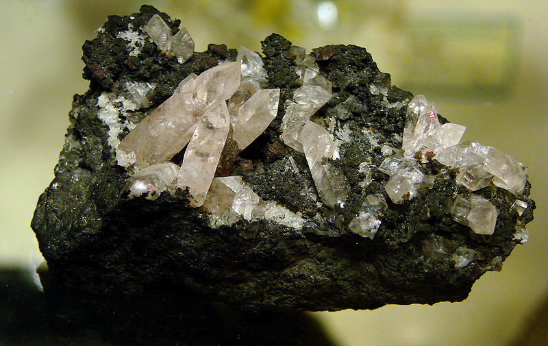 Un pedazo de roca negra con unos cristales puntiagudos blancos que emergen de la superficie.