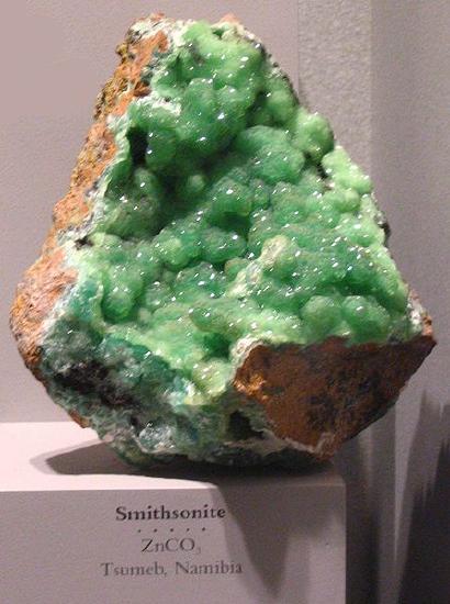 The inside of a large chunk of rock shows matte green crystals covering the entire interior. 