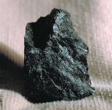 A chunk of black mineral with green and shiny tints. 
