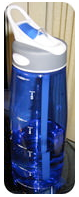 A blue transparent water bottle with a white and gray flip-top lid, sitting on a reflective surface.