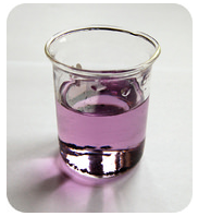 A small glass beaker containing a purple liquid on a white surface.