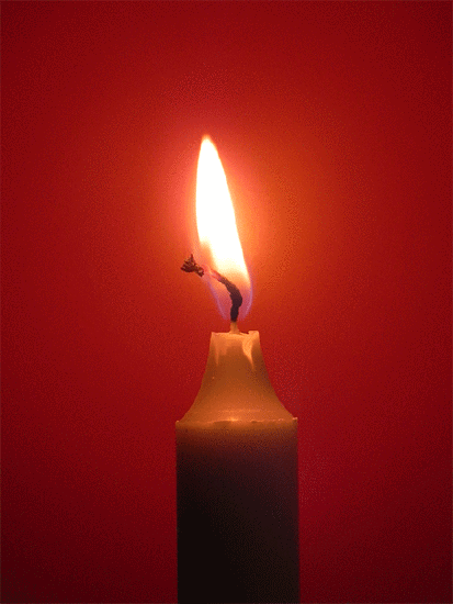 A candle burning against a red background.